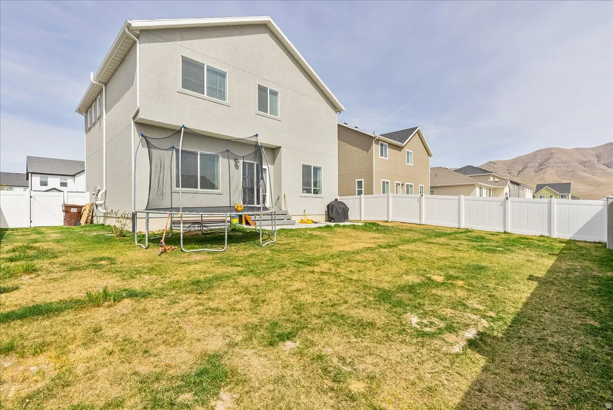 Rear view of house featuring a fenced backyard, stucco siding, a gate, a trampoline, and a mountain view