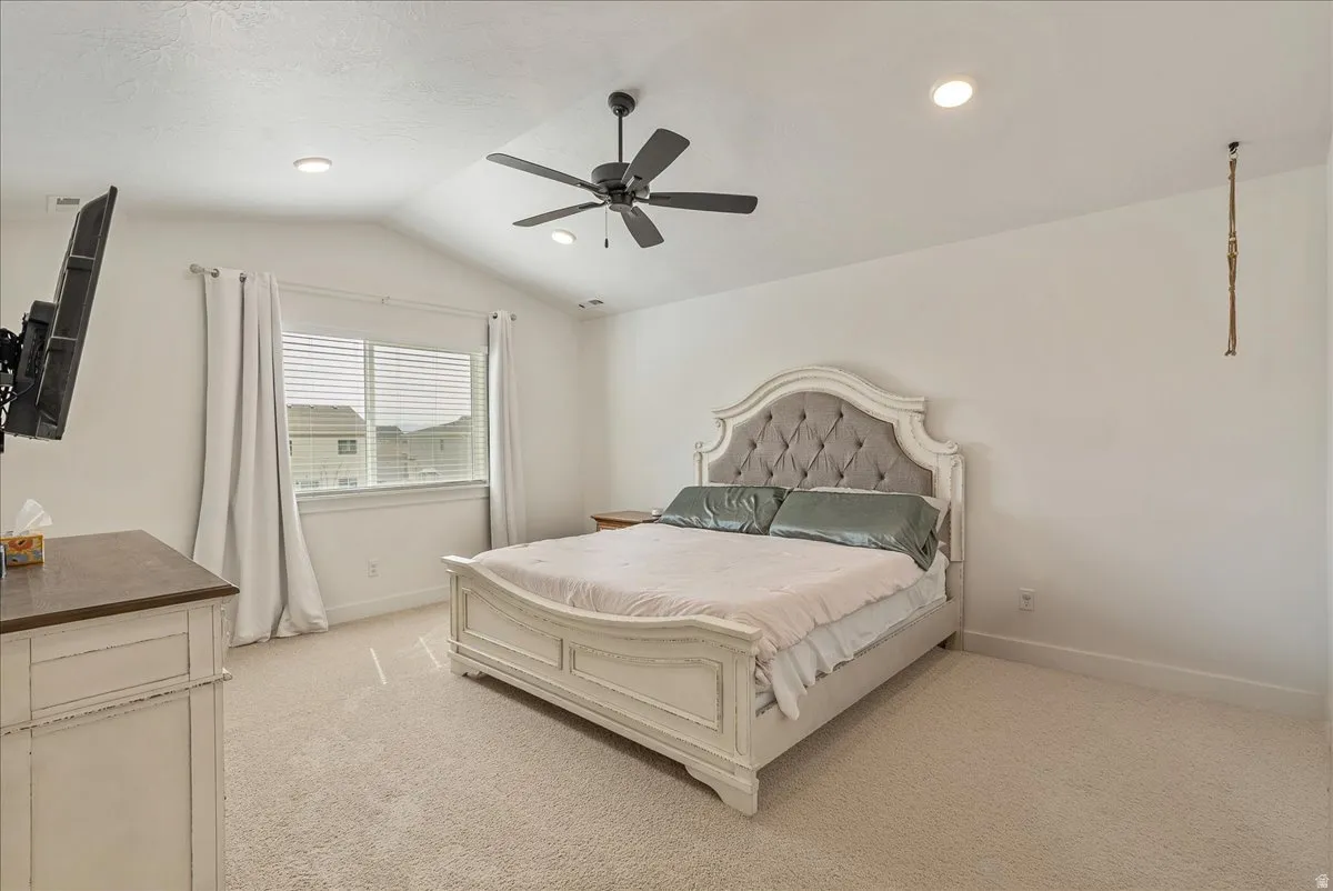 Bedroom with light colored carpet and a ceiling fan