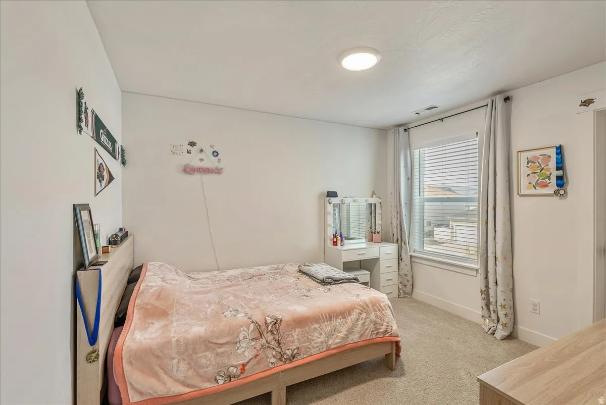 Bedroom with light colored carpet and baseboards