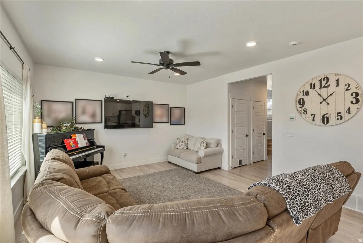Living room featuring light wood finished floors, ceiling fan, and recessed lighting