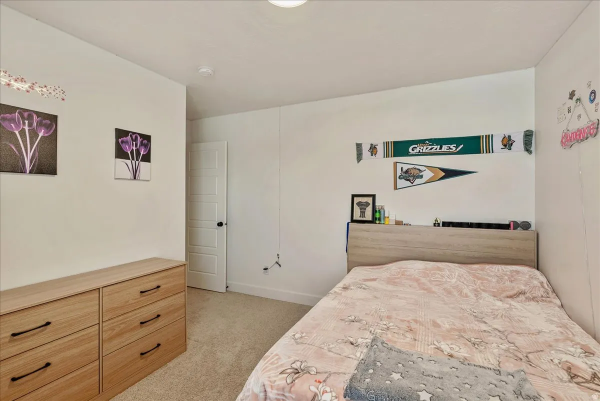 Bedroom with light colored carpet and baseboards