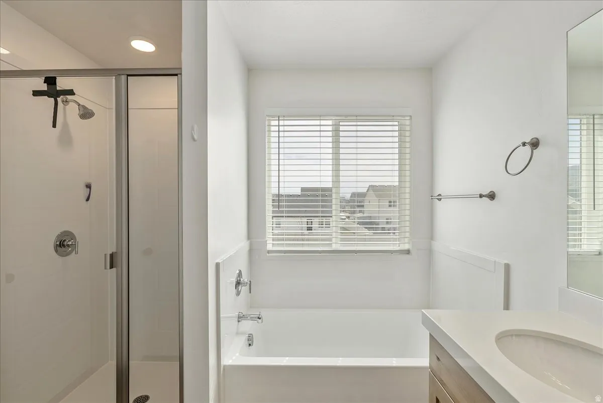 Bathroom featuring vanity, a bath, and a stall shower