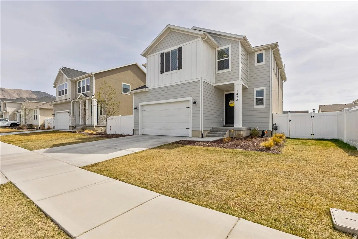 Traditional home featuring a gate, a garage, board and batten siding, driveway, and a residential view