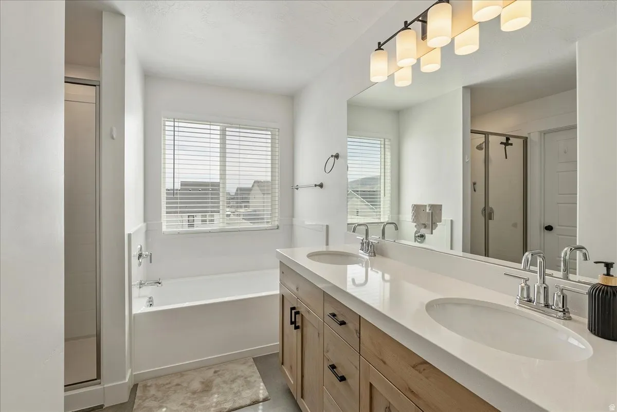 Bathroom featuring a shower stall, double vanity, and a bath