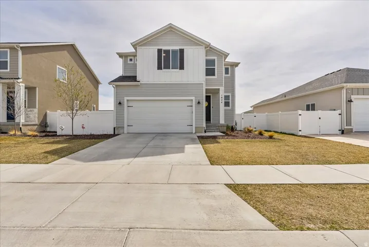 View of front facade with a gate, board and batten siding, driveway, and an attached garage