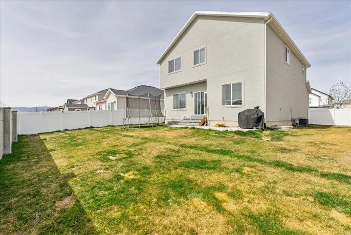 Back of house featuring a fenced backyard, a trampoline, and entry steps