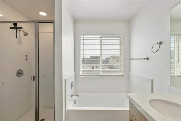 Bathroom featuring vanity, a bath, and a stall shower
