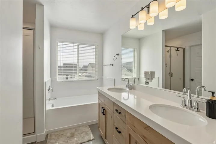 Bathroom featuring a shower stall, double vanity, and a bath