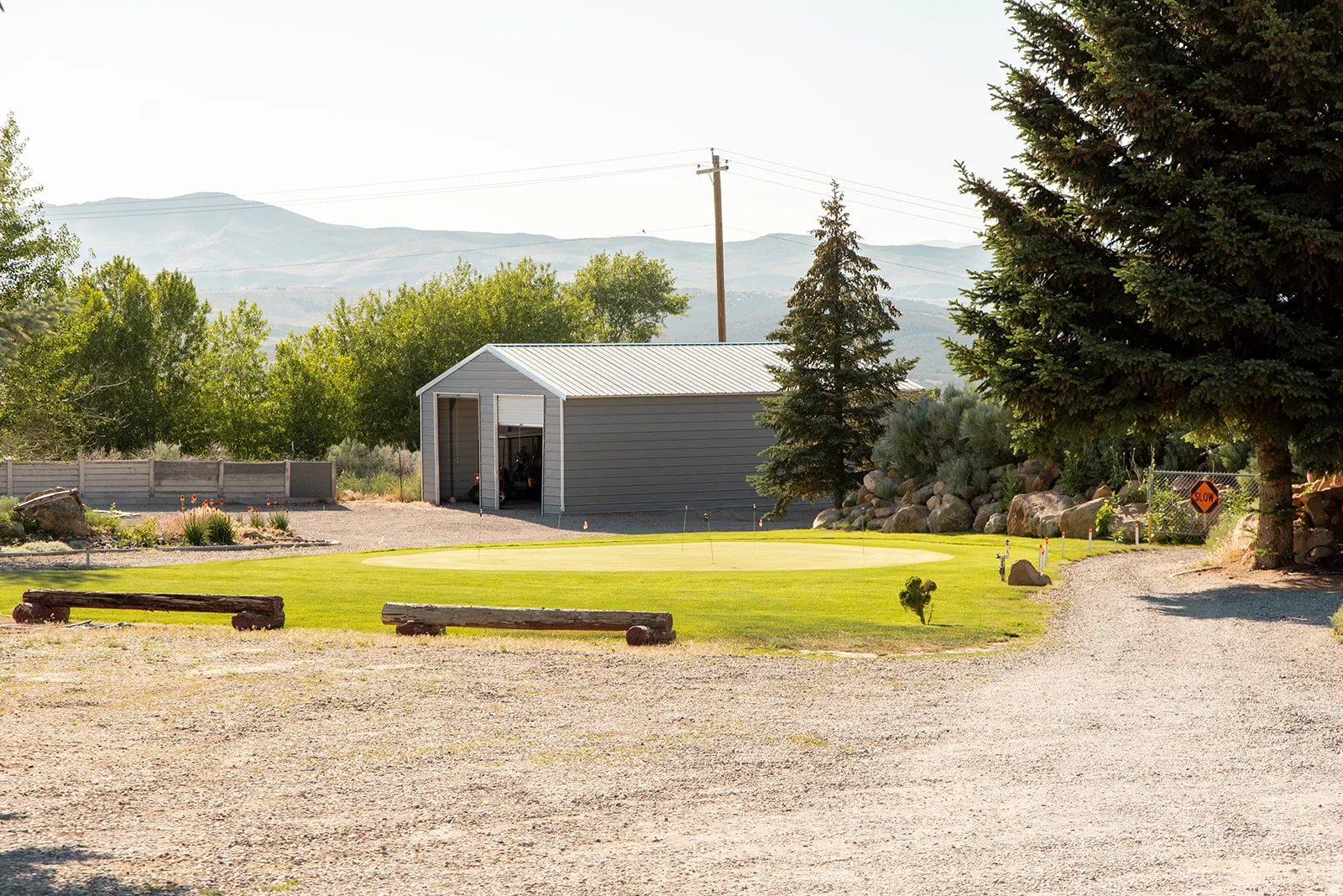 View of yard with an outdoor structure, a mountain view, a putting green, and an outbuilding