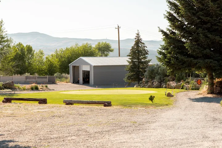 View of yard with an outdoor structure, a mountain view, a putting green, and an outbuilding