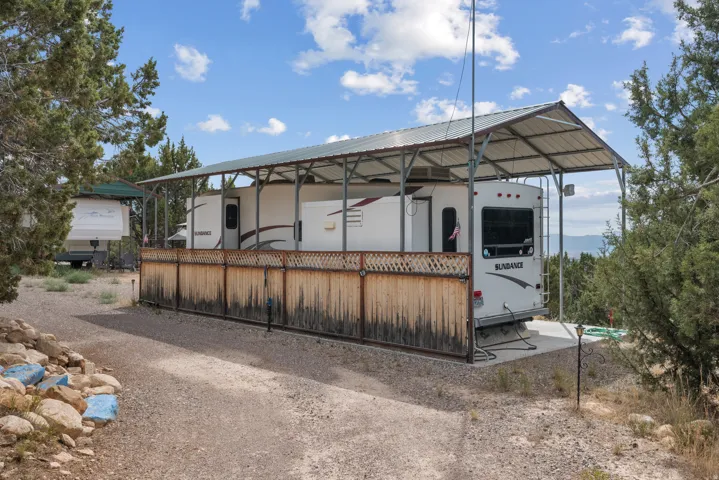 Attached covered structure with a metal roof and a wooden lattice privacy fence