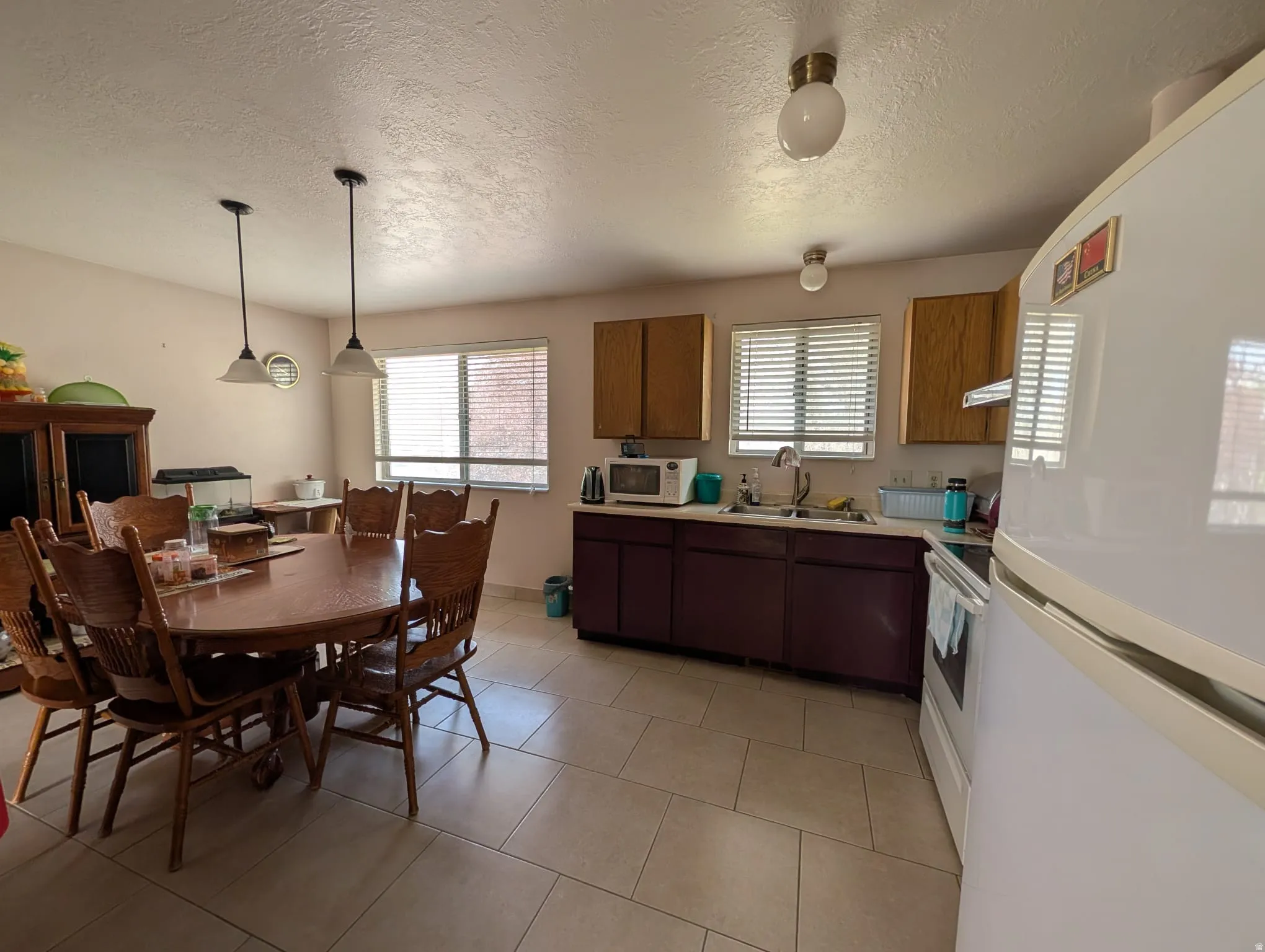 Kitchen with white appliances, light countertops, a textured ceiling, pendant lighting, and light tile patterned floors