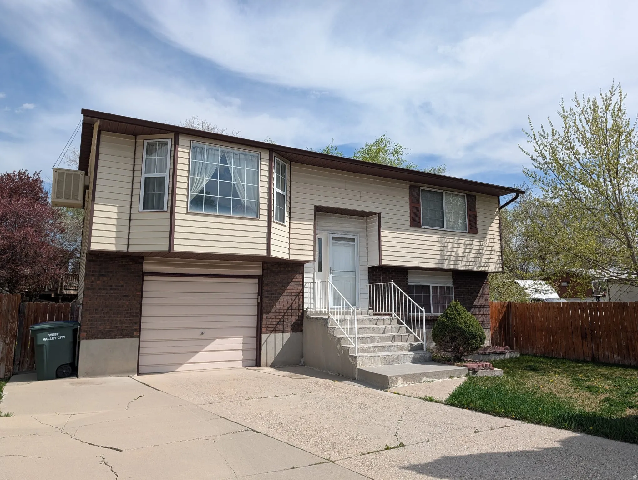 Split foyer home featuring brick siding, an attached garage, and driveway
