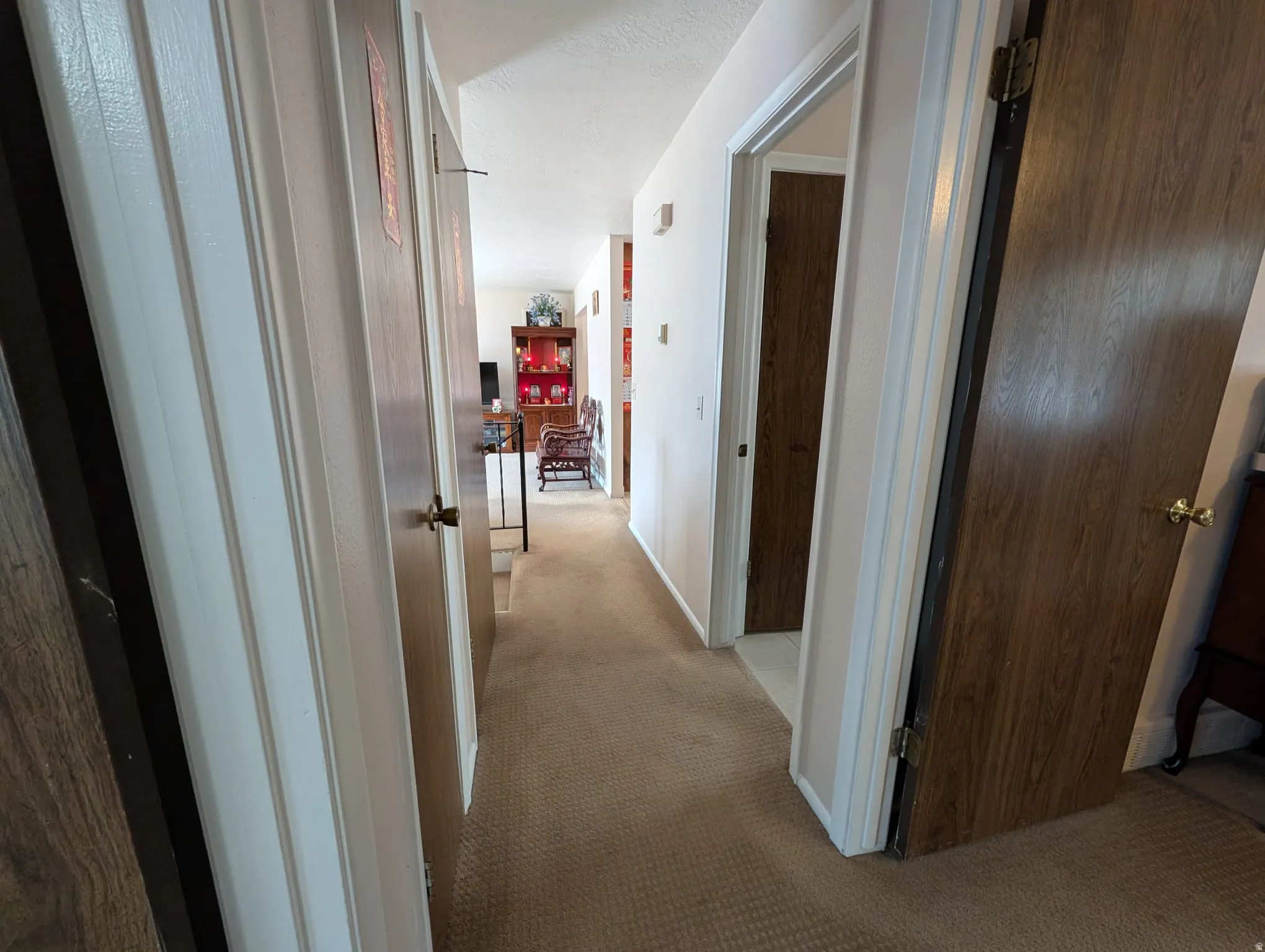 Hallway with light colored carpet and a textured ceiling