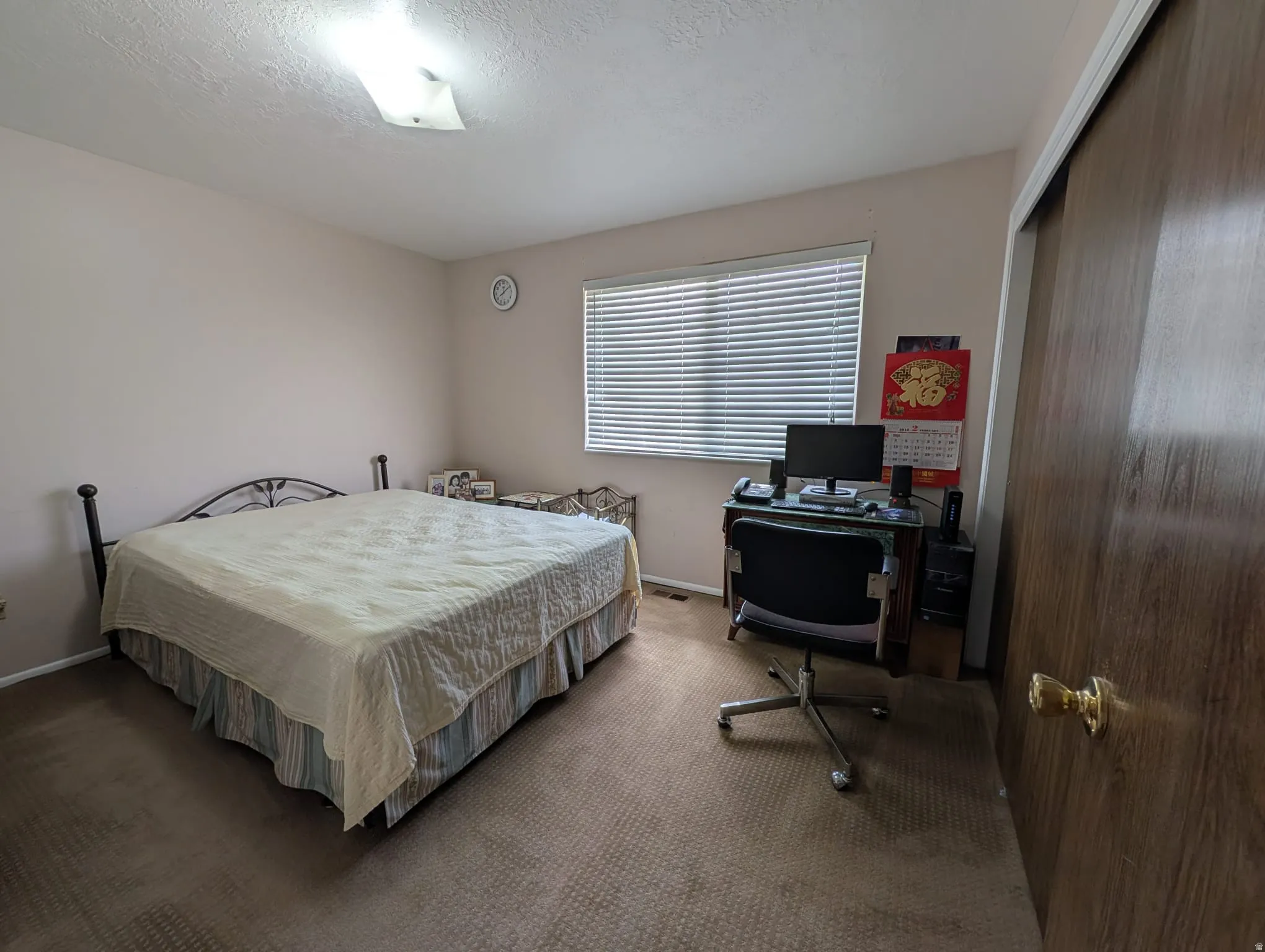 Carpeted bedroom featuring an office area, a closet, and a textured ceiling