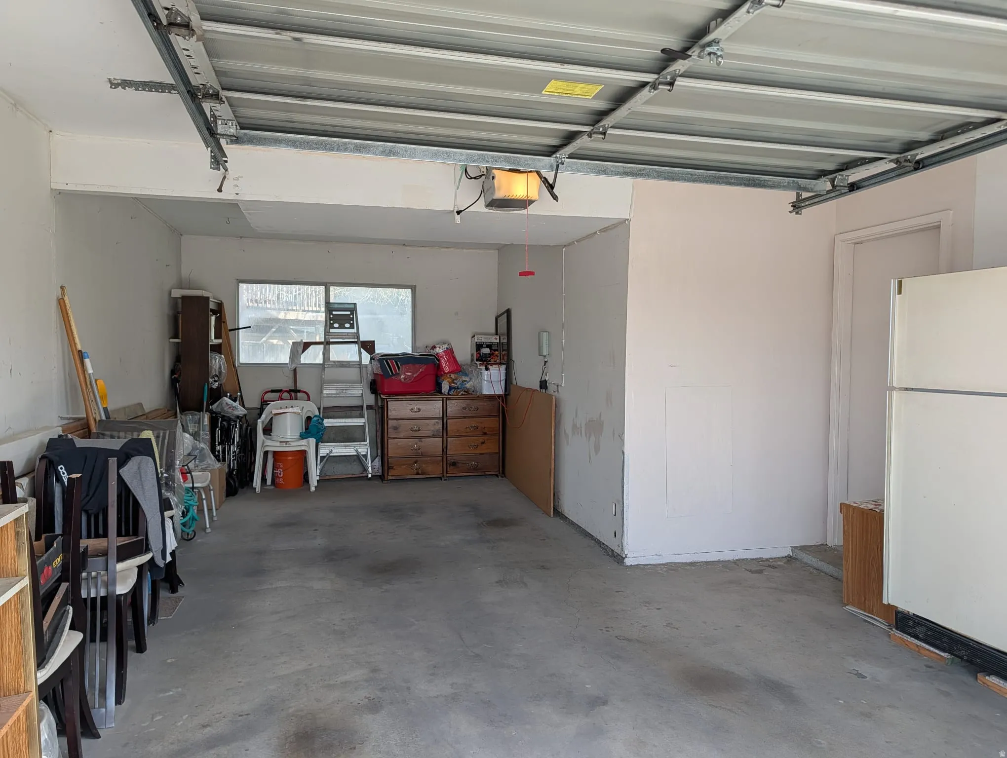 Garage featuring freestanding refrigerator and a garage door opener