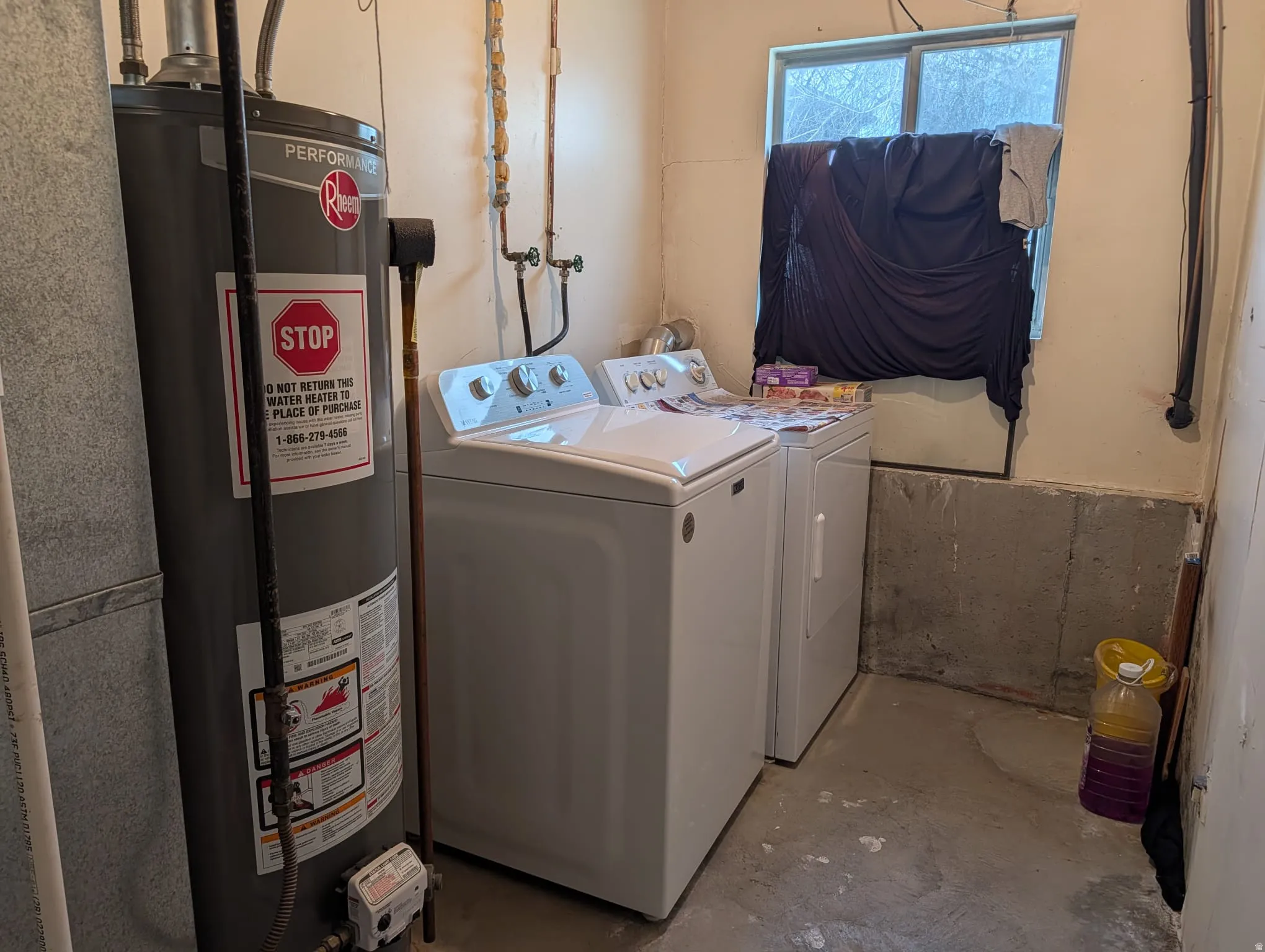 Laundry area with concrete flooring, water heater, and independent washer and dryer