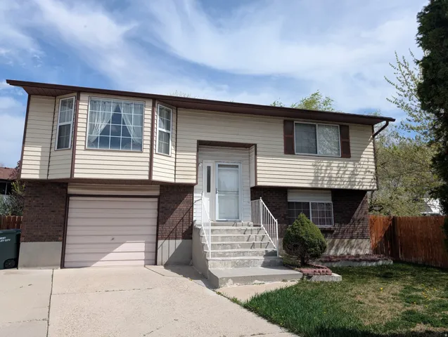 Bi-level home featuring brick siding, a garage, and concrete driveway