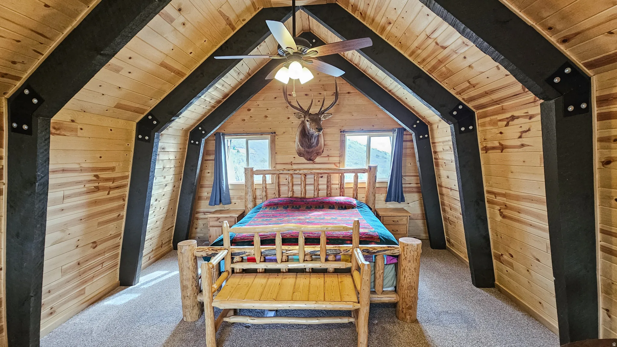 Loft with wooden walls, a wood ceiling with exposed beams, and carpet