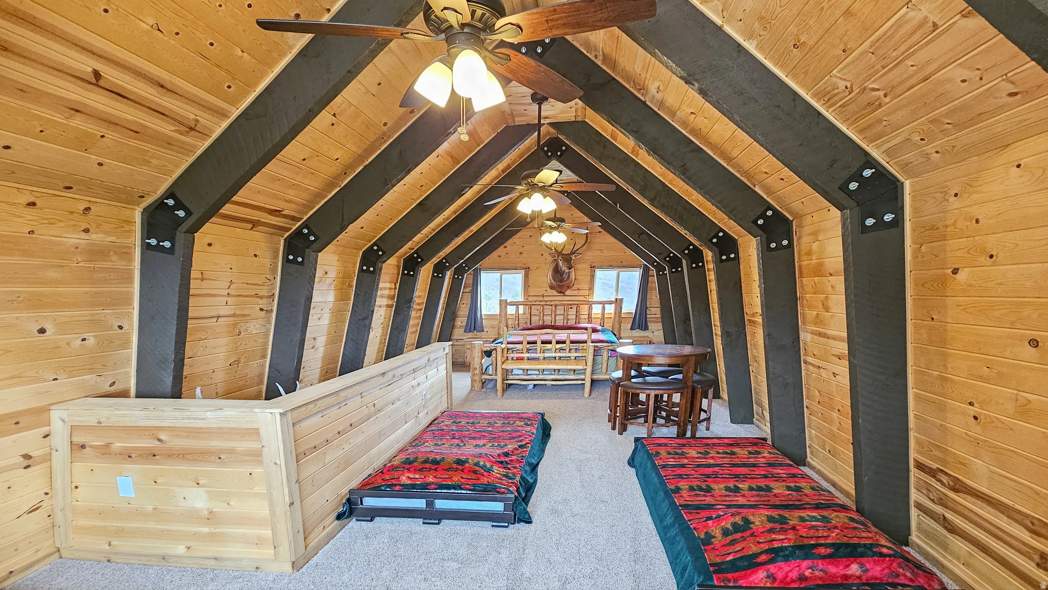 Loft with wooden walls, a wood ceiling with exposed beams, and carpet