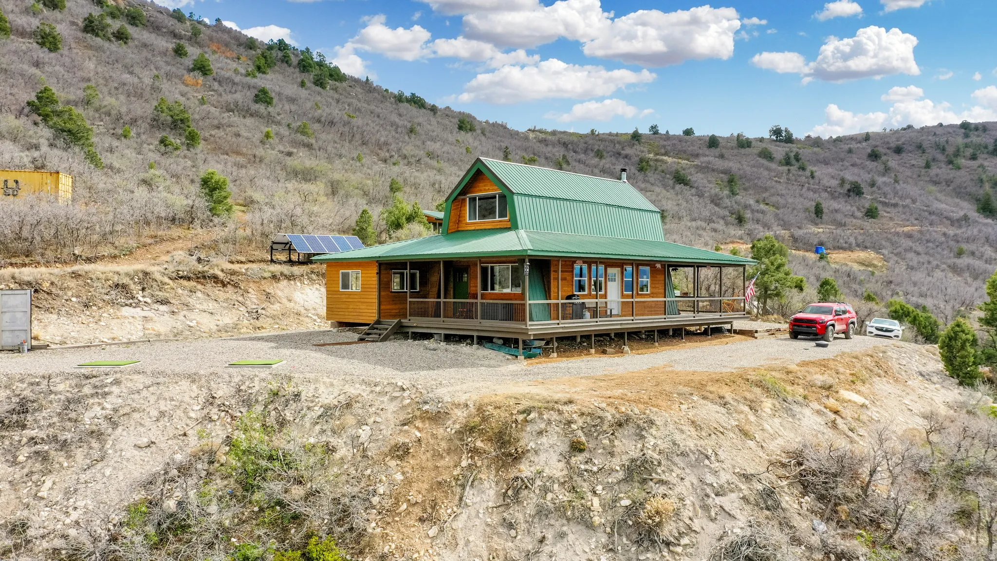 Rustic home with covered porch, a mountain view, ground mounted solar panels, and a metal roof