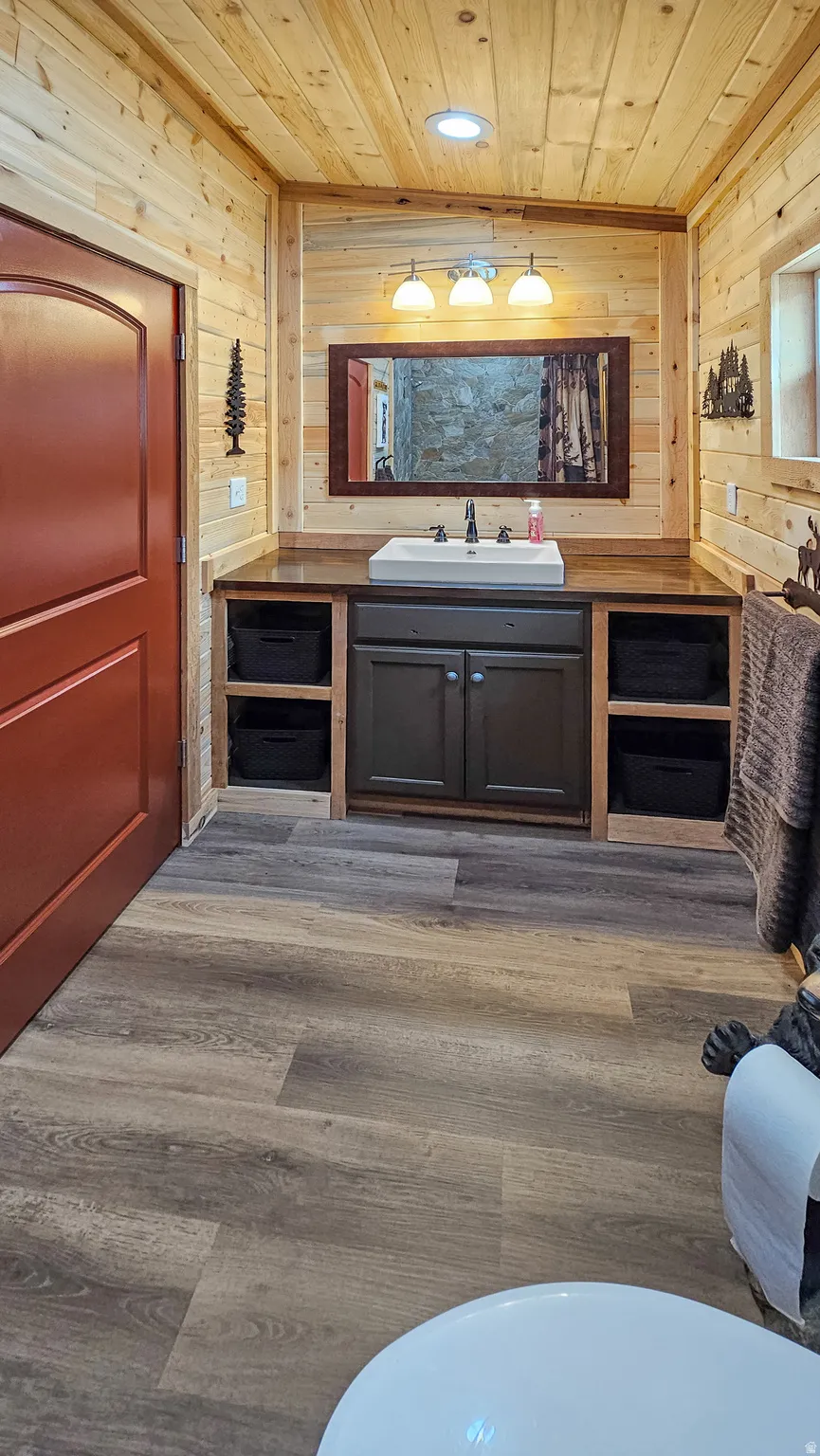 Bathroom featuring wooden walls, vanity, dark wood-style flooring, wood ceiling, and recessed lighting