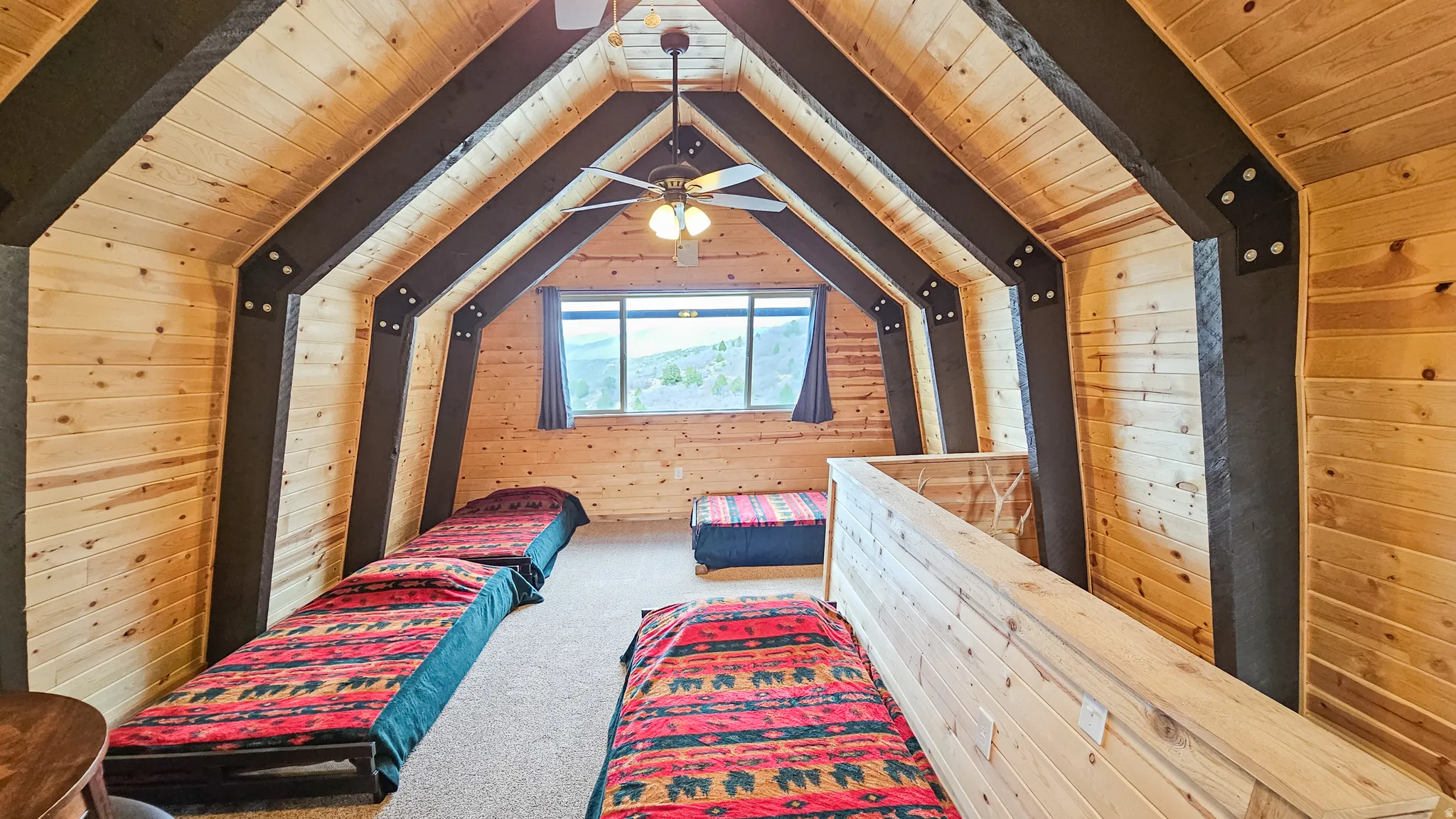 Loft with wooden walls, a wood ceiling with exposed beams, and carpet