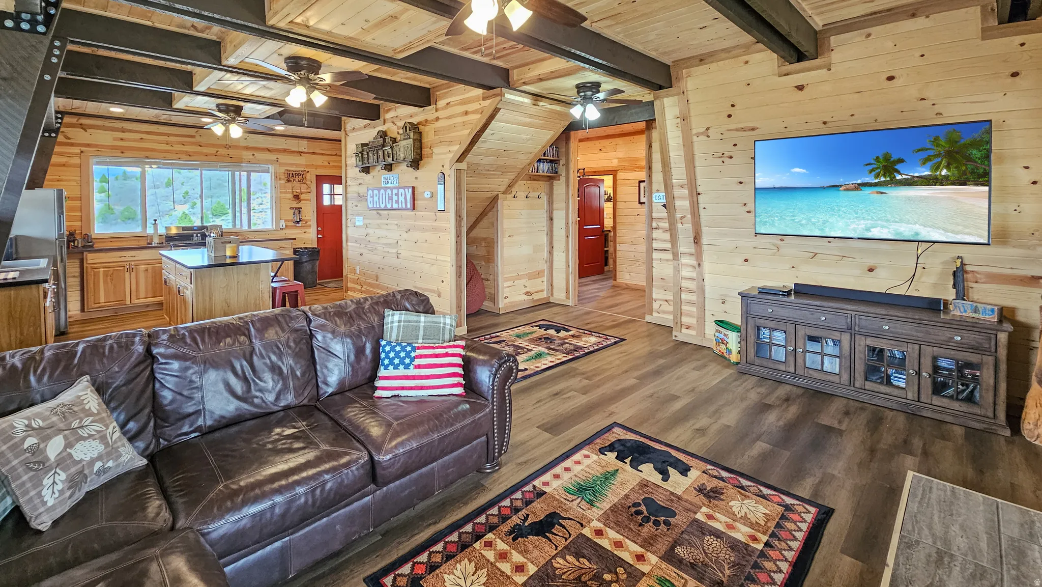 Living room featuring wood walls, dark wood-style flooring, and a wooden ceiling with exposed beams