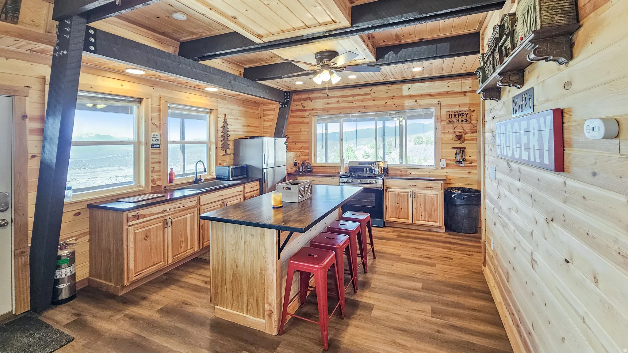 Kitchen featuring wooden walls, wooden ceiling, dark wood-style flooring, a center island, and a breakfast bar