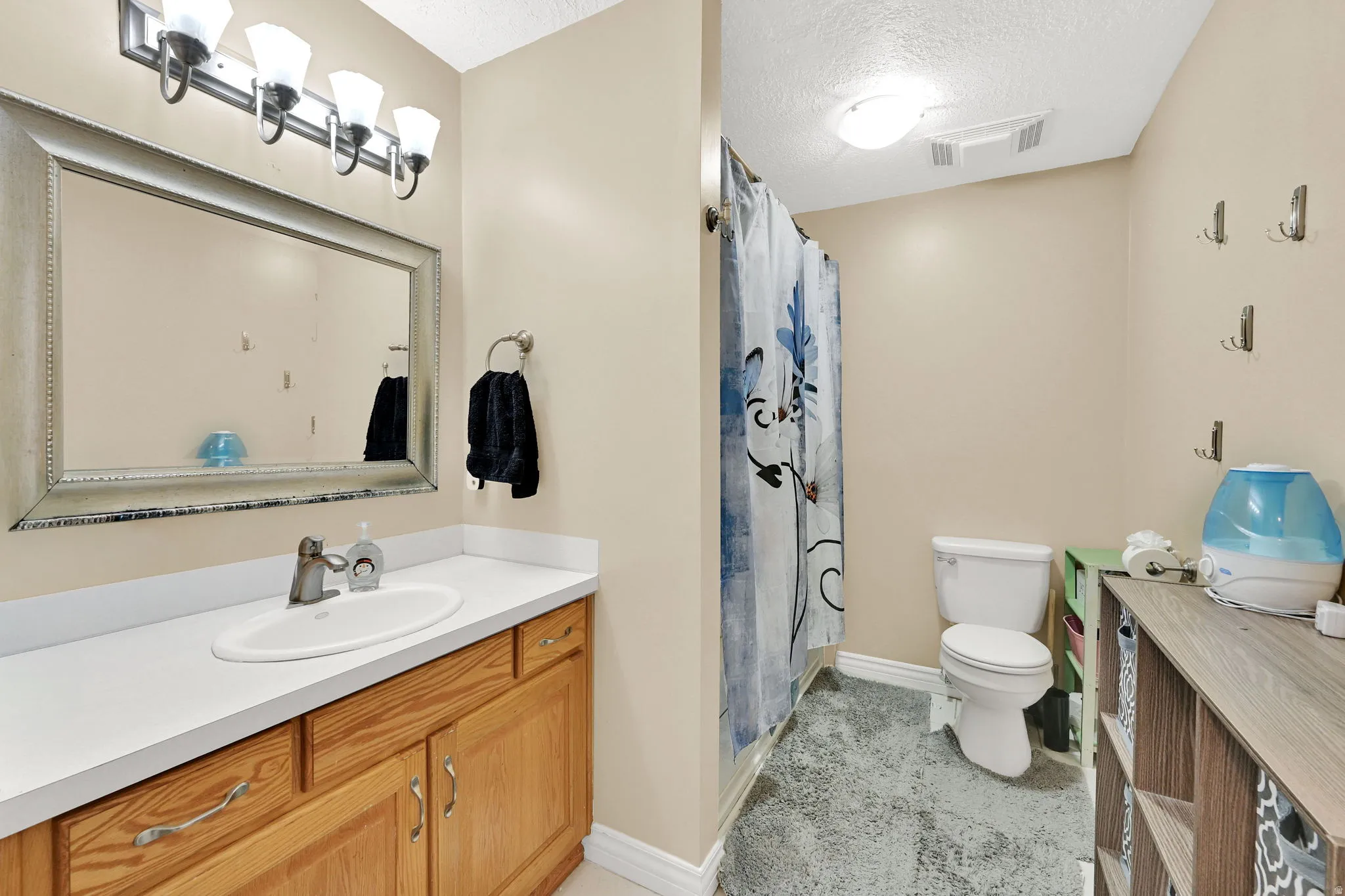 Full bathroom featuring vanity, a shower with curtain, and a textured ceiling