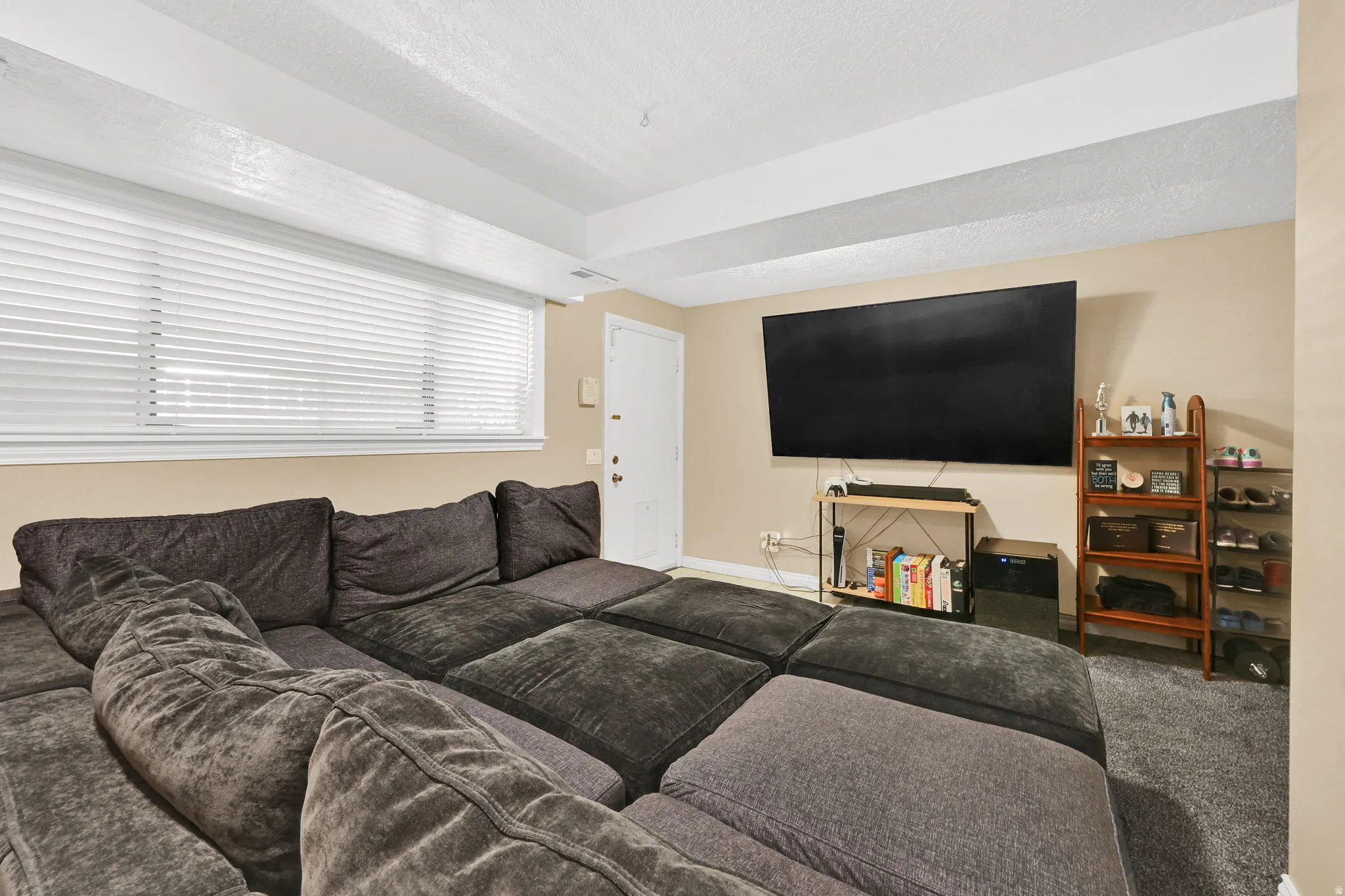 Carpeted living area featuring a textured ceiling and baseboards