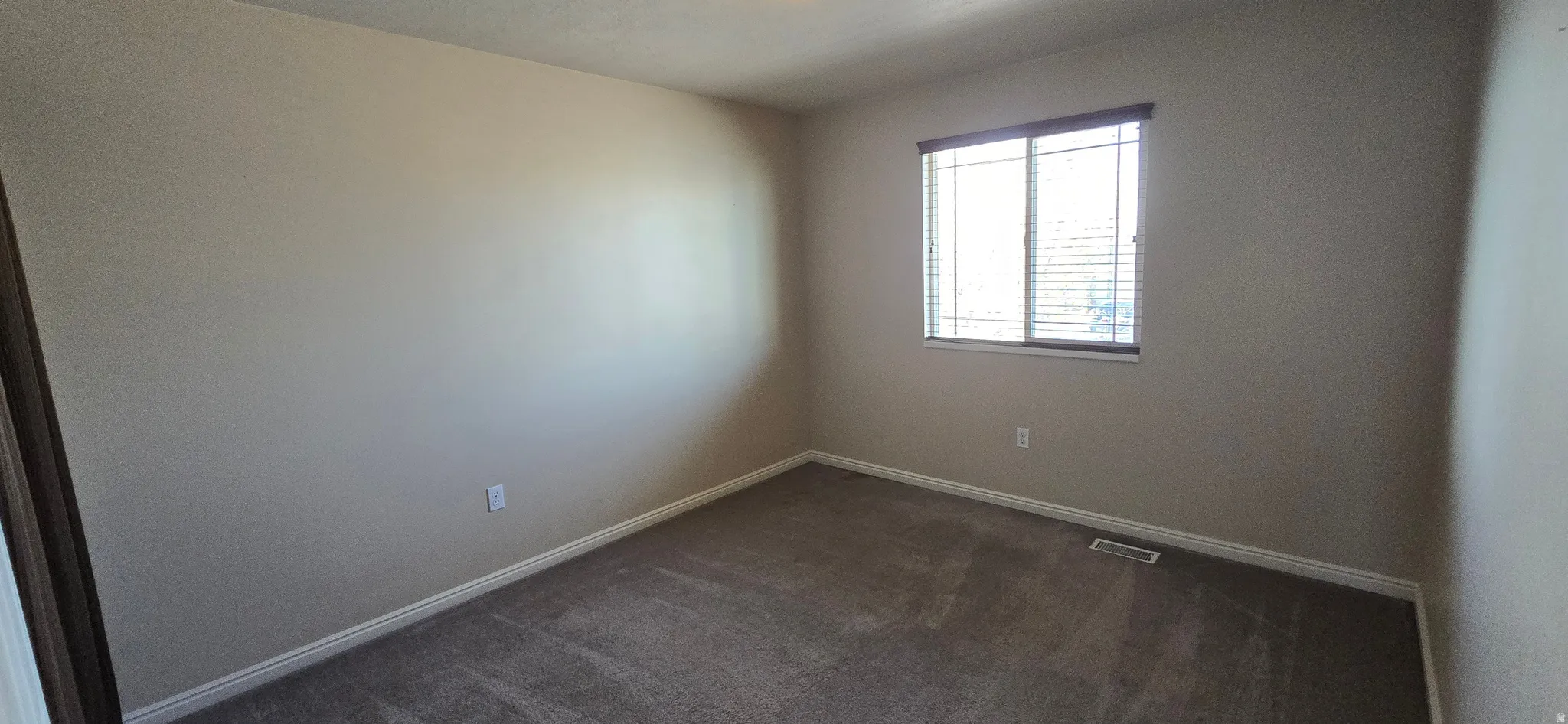 Spare room featuring dark colored carpet and baseboards