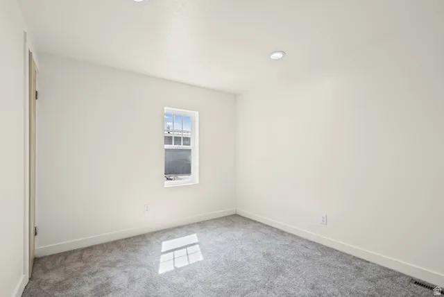 Unfurnished room with light colored carpet and baseboards