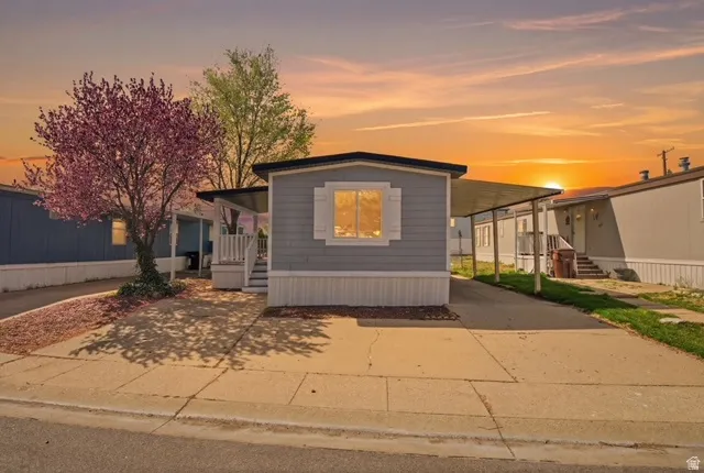 Manufactured / mobile home with covered porch, driveway, and an attached carport