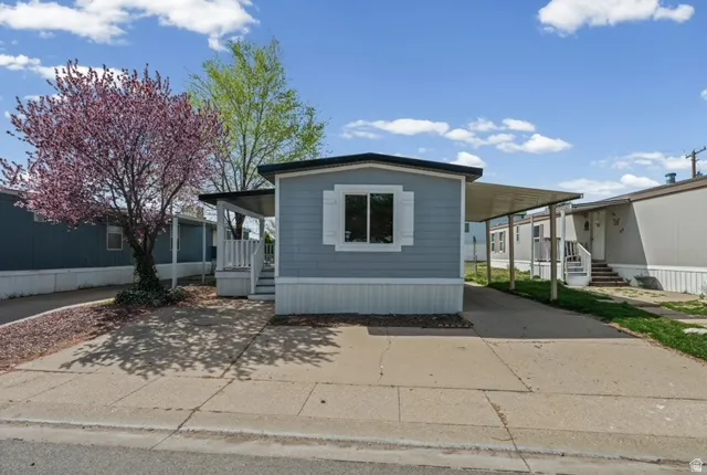 Manufactured / mobile home featuring driveway, an attached carport, and a porch