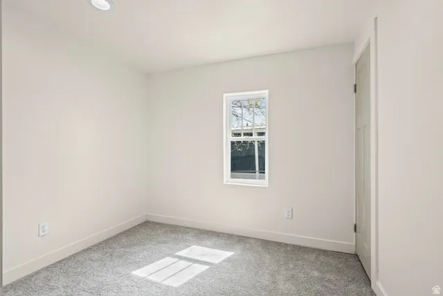 Unfurnished room featuring baseboards and light colored carpet