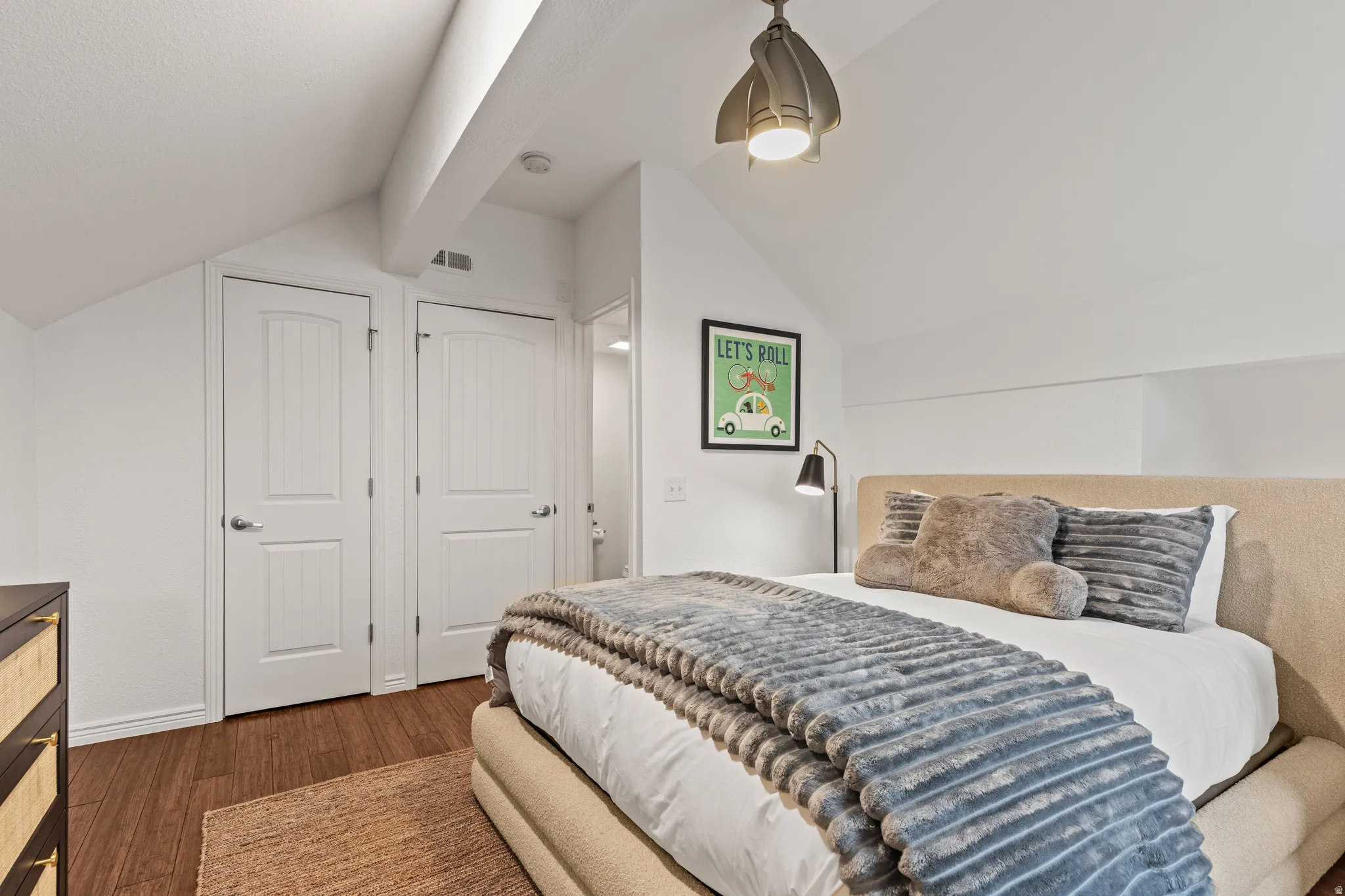 Bedroom with dark wood finished floors, lofted ceiling, and a closet