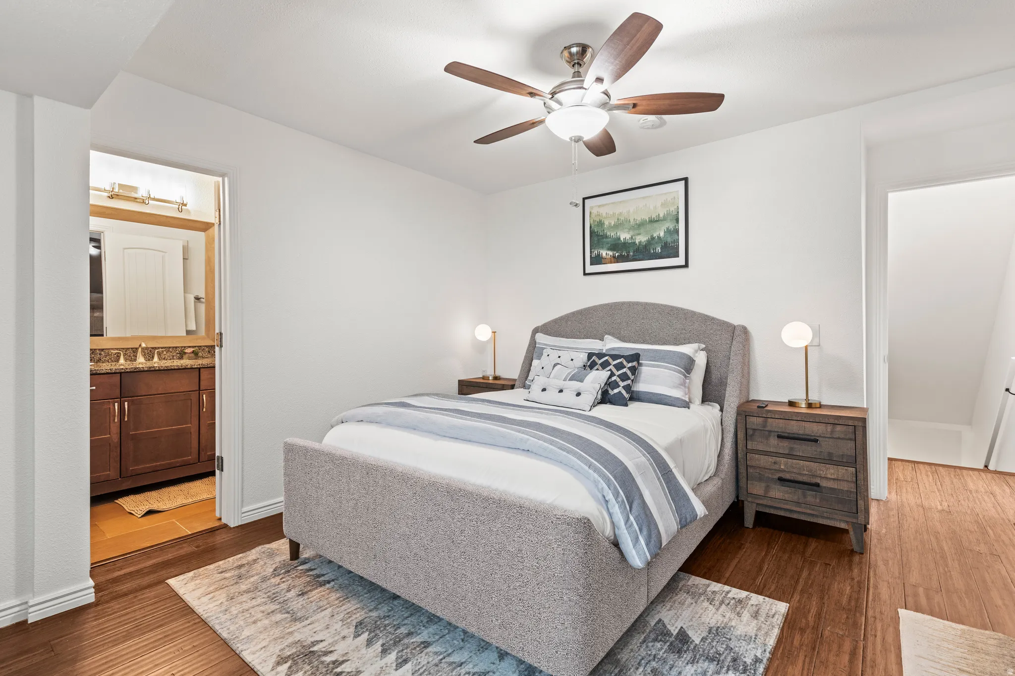 Bedroom with dark wood finished floors, ceiling fan, and ensuite bath