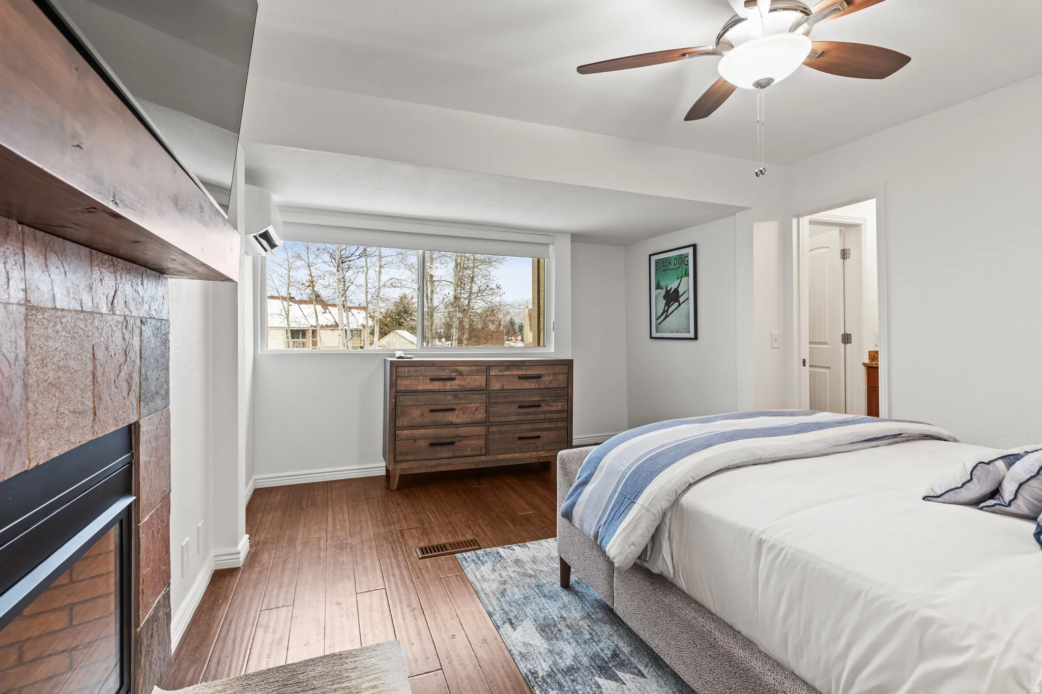 Bedroom featuring a fireplace, hardwood / wood-style flooring, and ceiling fan