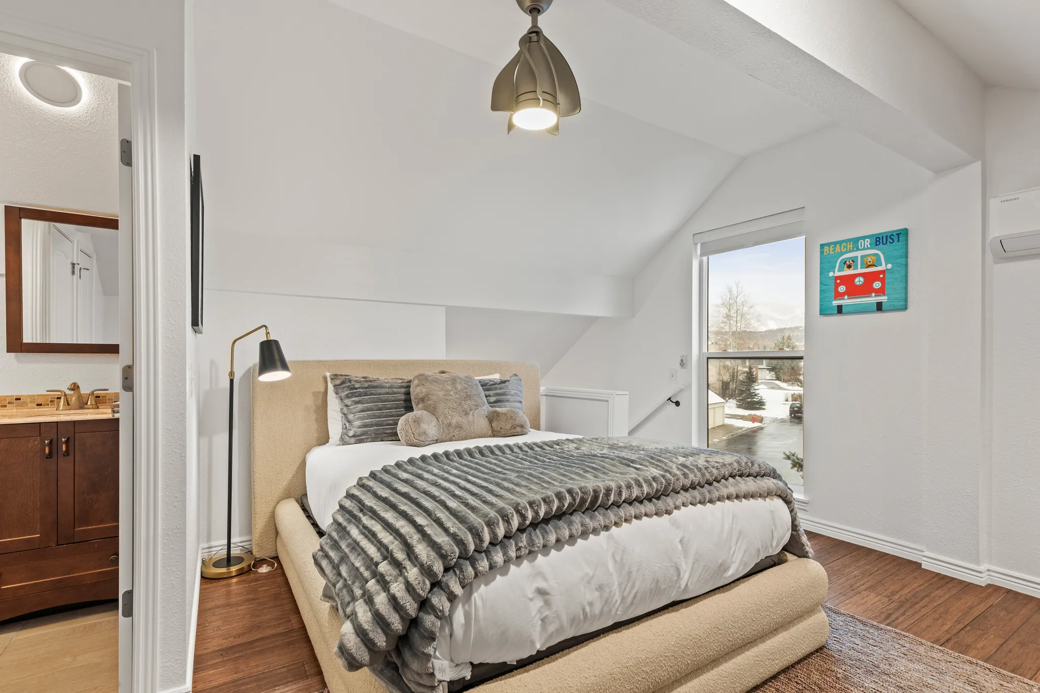 Bedroom featuring light wood-style floors, connected bathroom, and vaulted ceiling