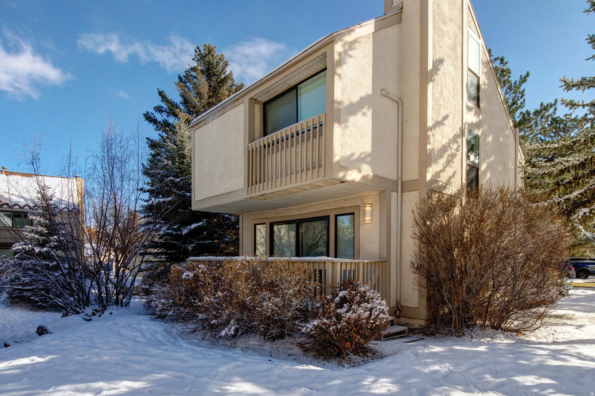 Snow covered property with a balcony and stucco siding