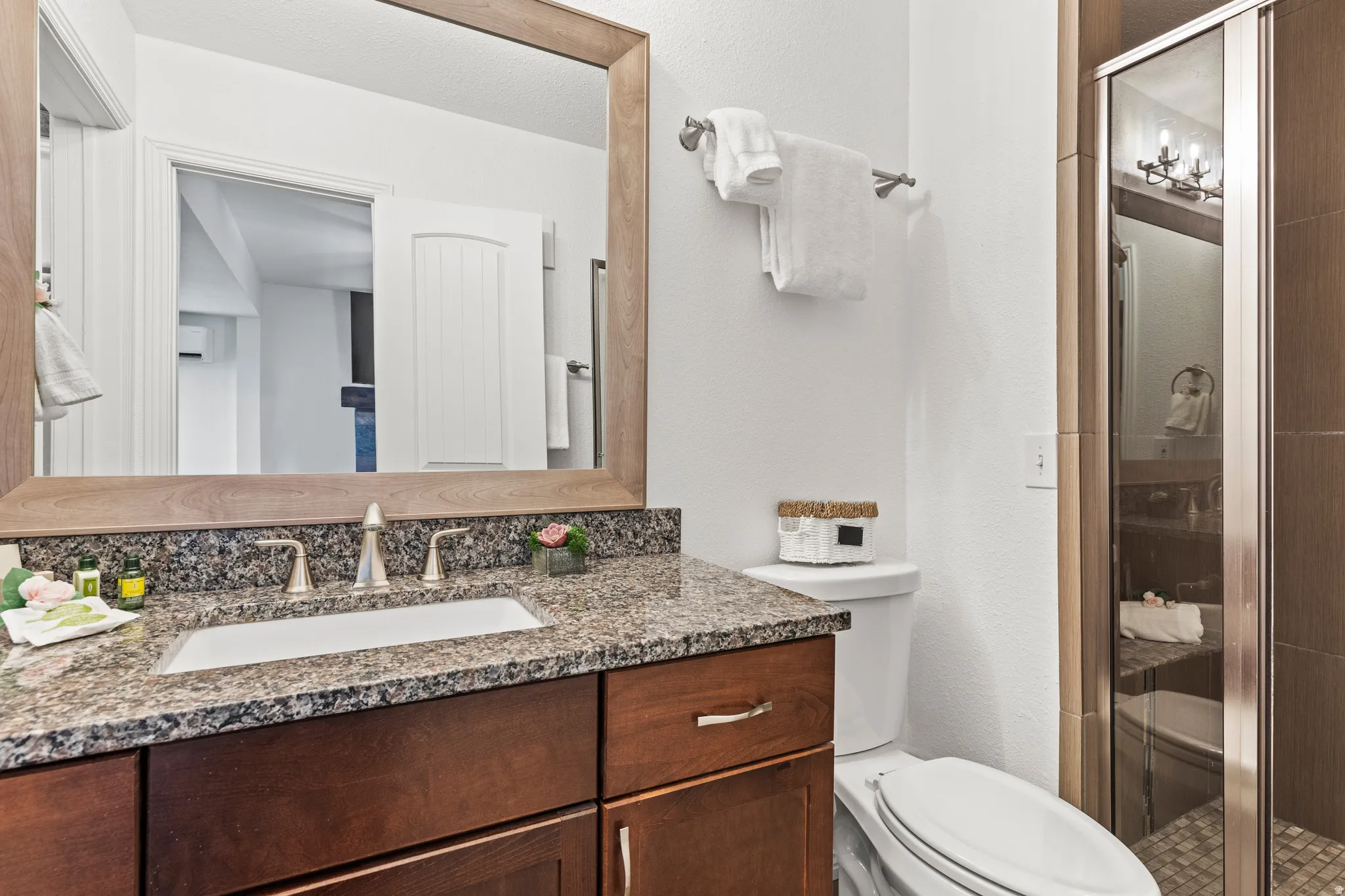 Bathroom featuring a stall shower, vanity, and a textured wall