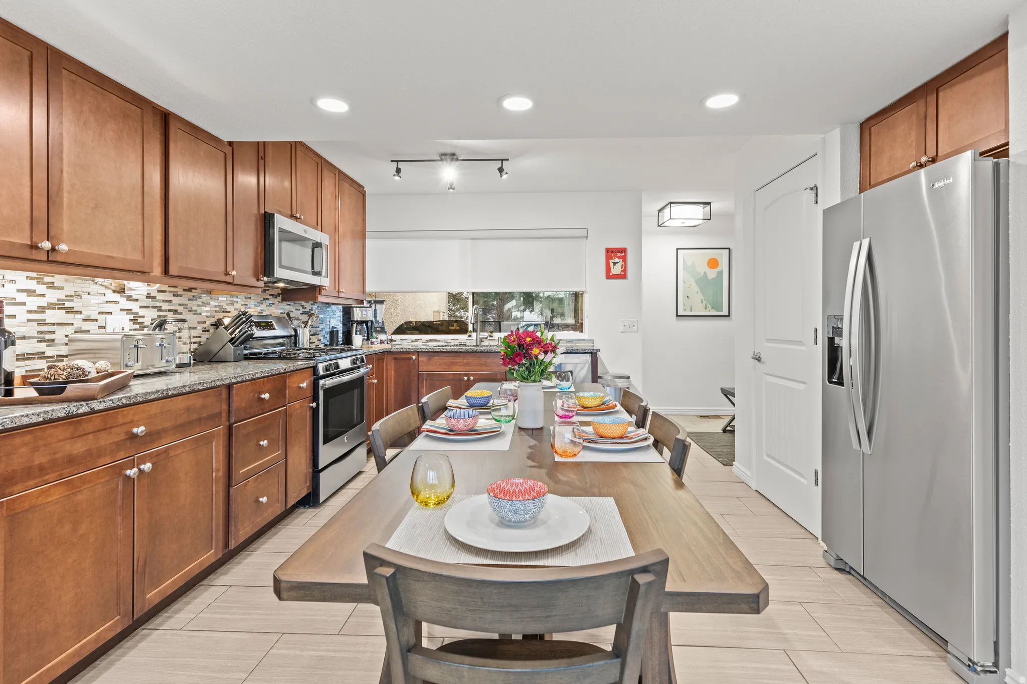 Kitchen with stainless steel appliances, wood finish cabinetry, dark stone counters, decorative backsplash, and recessed lighting