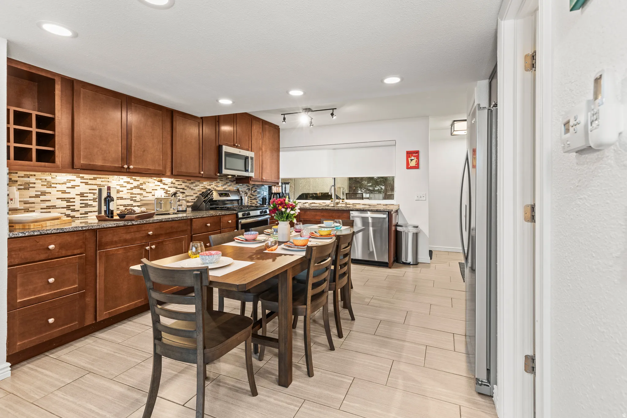 Kitchen with stainless steel appliances, light stone counters, decorative backsplash, recessed lighting, and wood tiled floors