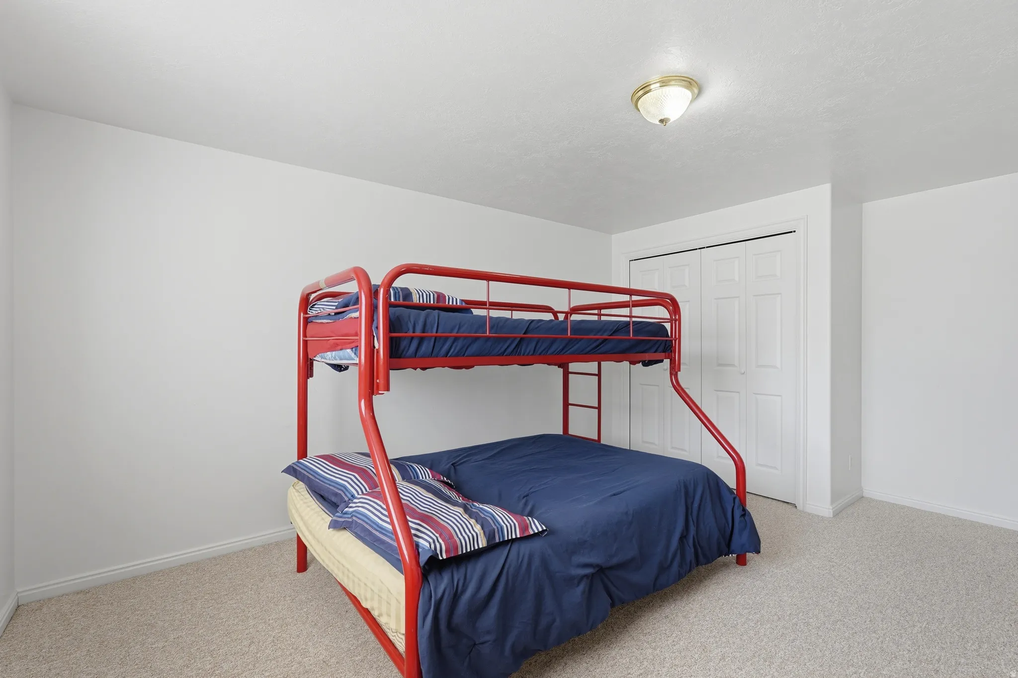 Bedroom with light colored carpet and a closet