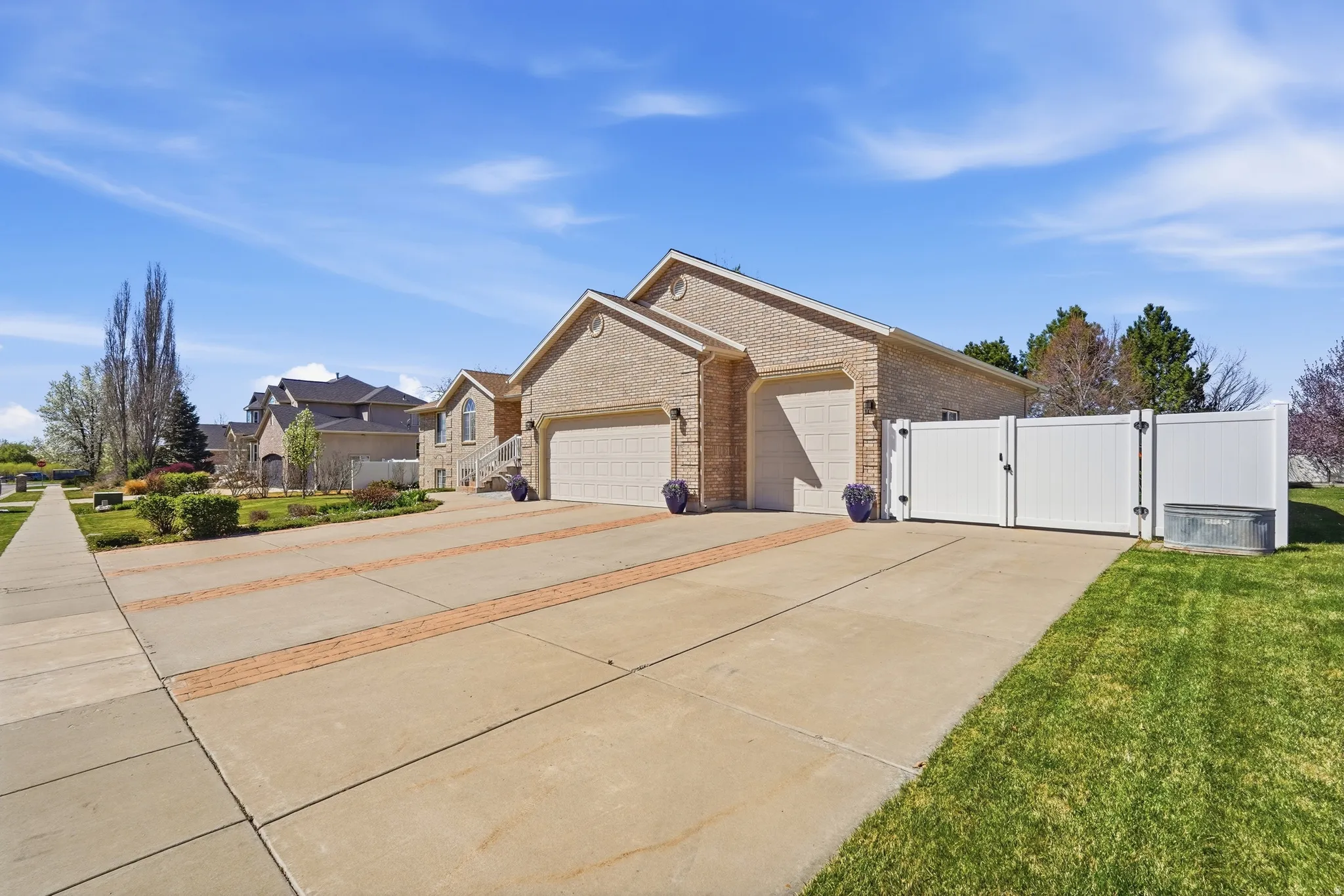 View of home's exterior featuring a gate, concrete driveway, brick siding, an attached garage, and a residential view