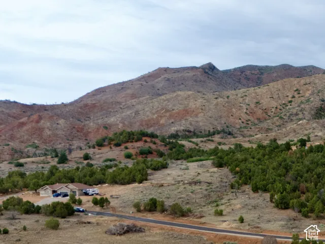 Paved road, natural landscaping, mountainous terrain, wooded areas, winding road