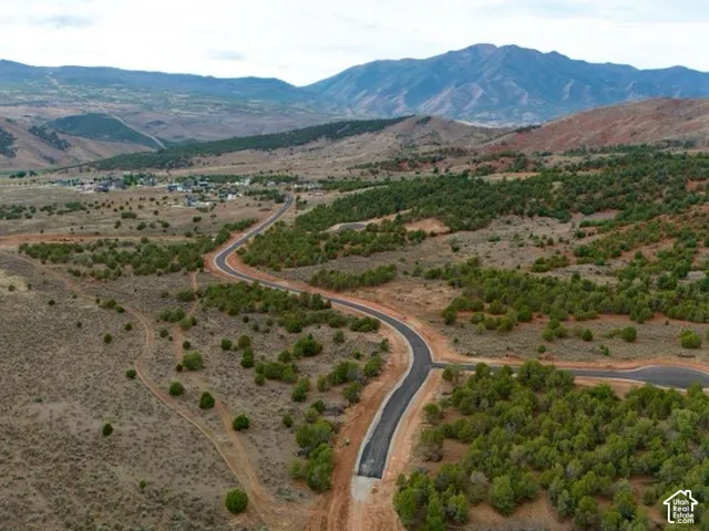 Expansive landscape featuring distant mountains, established community, and paved roads with cul-de-sac