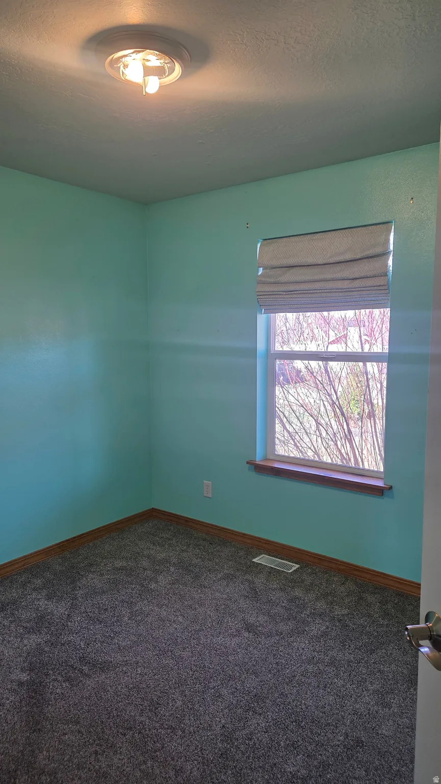 Bedroom 2 with a textured ceiling and dark colored carpet