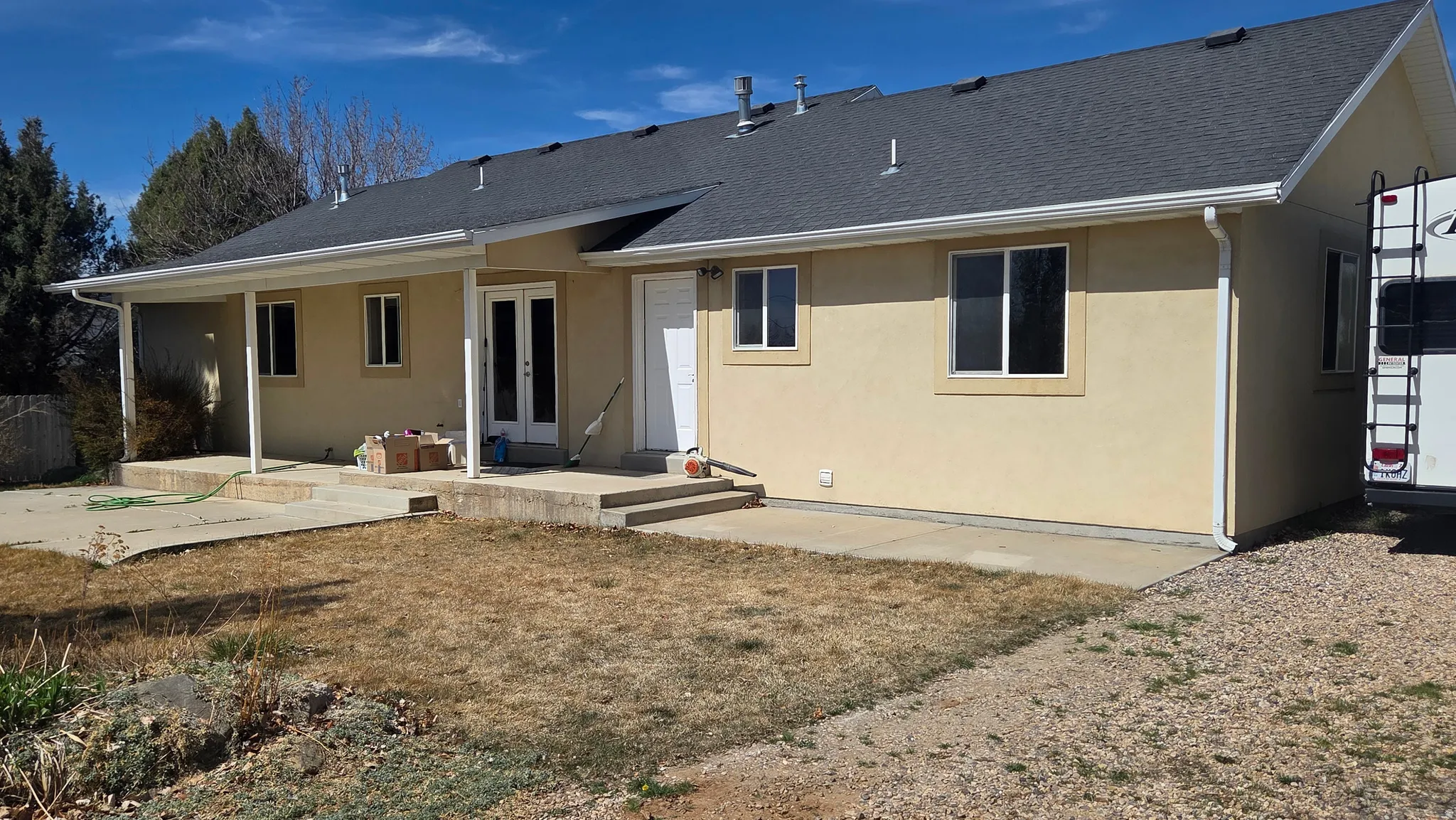 Rear view of house with french doors, stucco siding, roof with shingles, and a patio area